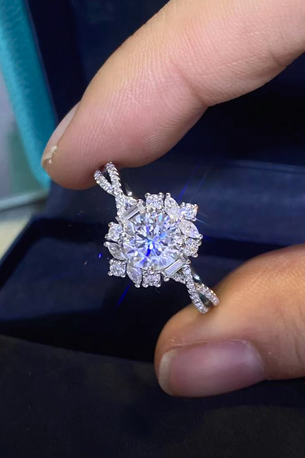 Floral 2 Carat Moissanite Crisscross Engagement Ring held between fingers, showcasing its brilliant sparkle and elegant design.