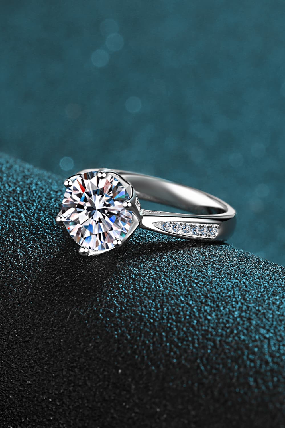 3 Carat Moissanite Rhodium-Plated Side Stone Ring on a textured background, showcasing its elegant design.
