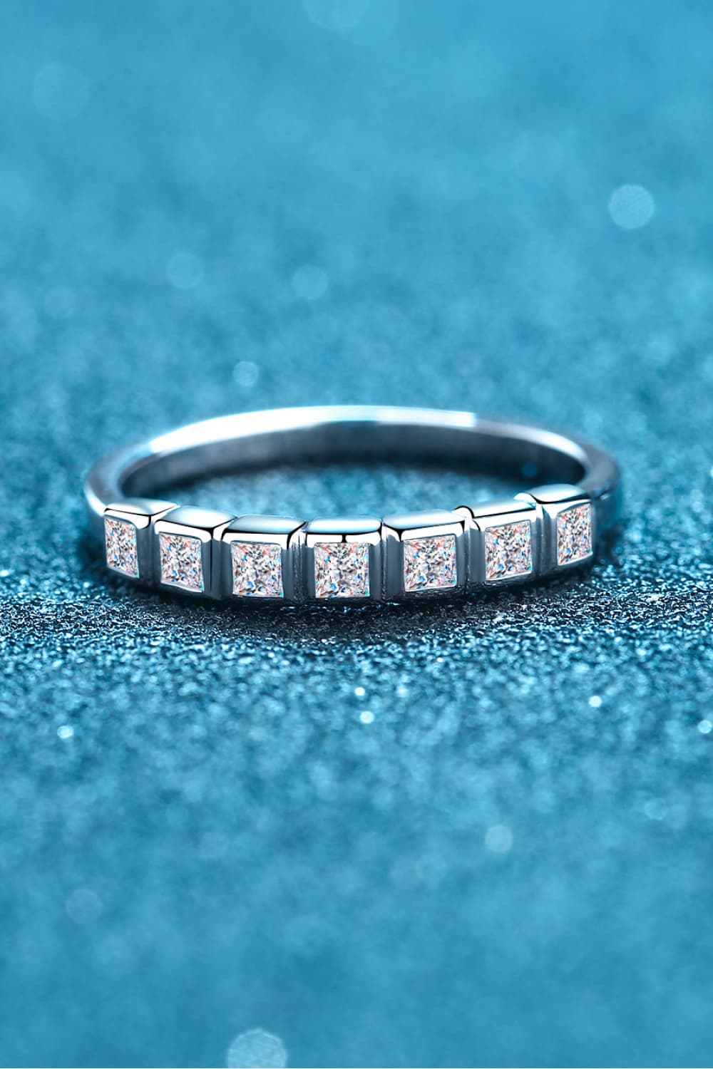 Moissanite Rhodium-Plated Half-Eternity Ring on shimmering blue background
